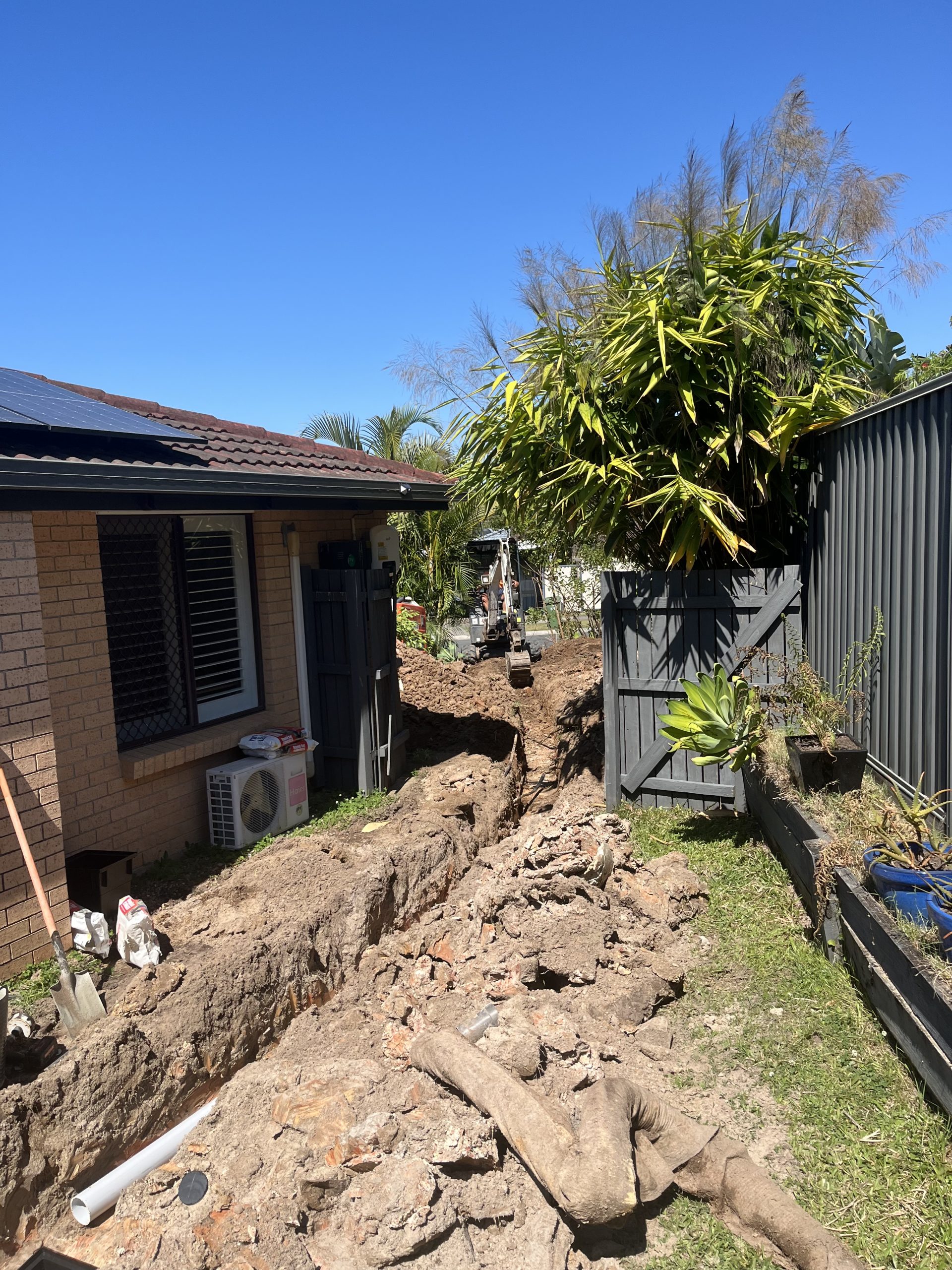 Open trench showing collapsed 90mm PVC stormwater pipe at a Labrador property, replaced with new pipe.